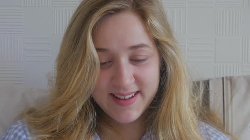 Young beautiful happy smiling blond woman in bed laughing