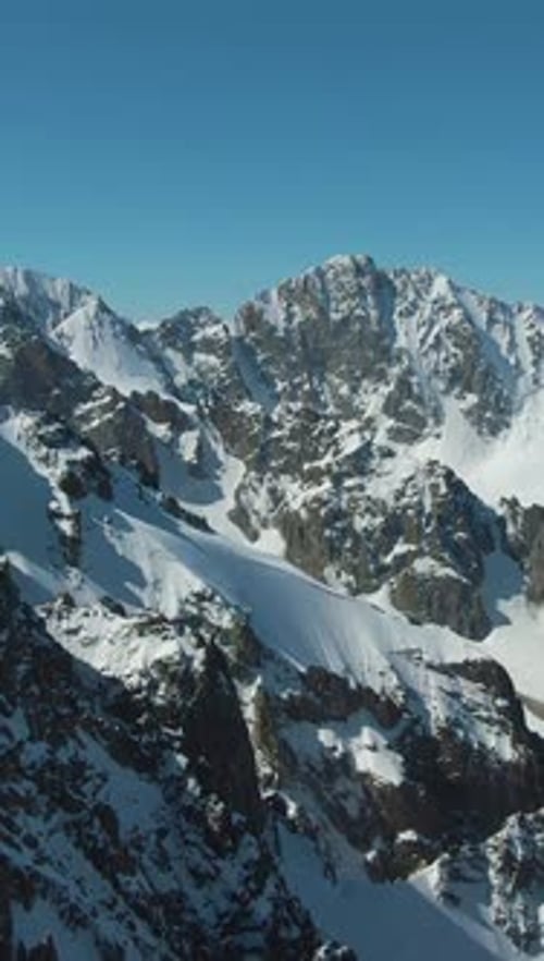 Montagnes enneigées bleues par temps ensoleillé, vue aérienne, vidéo verticale