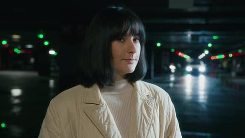 Woman Standing in a Dim Parking Garage at Night