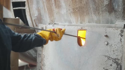 Person Placing Molten Material into Hot Oven