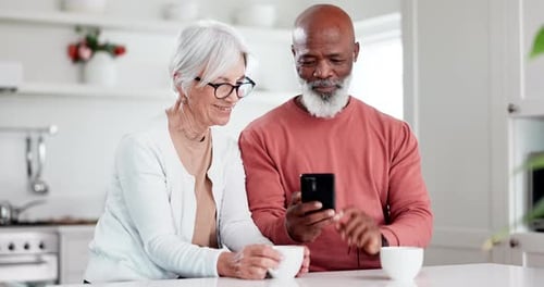 Senior Couple Looking at Mobile Phone in Kitchen
