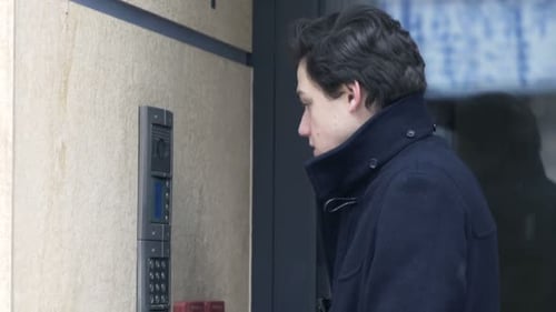 Young Teenager Talking on Intercom by Apartment Building Entrance Access