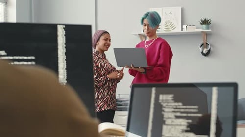 De jeunes collègues de divers horizons discutent au bureau du programmeur