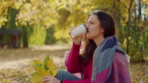 Caucasian Woman Drinking Coffee in Autumn Park