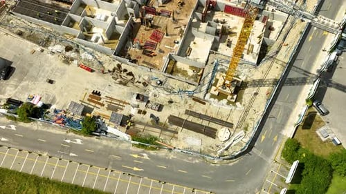Vista aérea de un sitio de construcción activo con grúas, trabajadores y cimientos de edificios en progreso