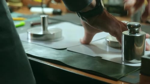 Craftsman Placing Metal Weight on Leather Material