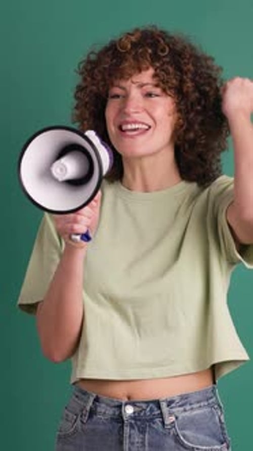 Excited Young Woman Screaming on Loudspeaker in Green Studio Vertical Footage