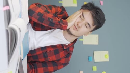 Young Adult Rubbing Eyes Tiredly at Table Indoors