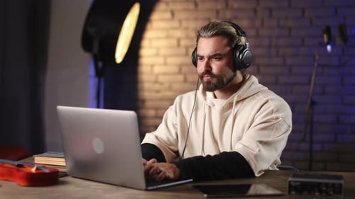 Man in Headphones Working on Laptop and Tablet at Studio