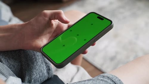 Nahaufnahme eines Teenagers, der ein Handy mit grünem Bildschirm benutzt