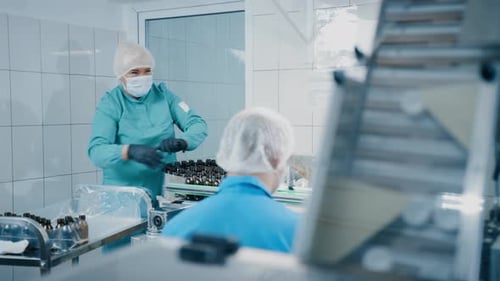 Workers Handling Medicine Bottles in Medical Production Facility