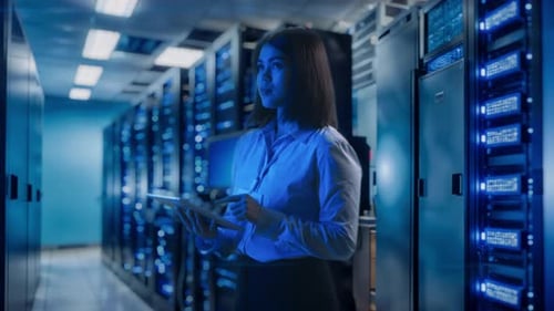 Female Data Center Worker Examining Server Rack and Using Digital Tablet