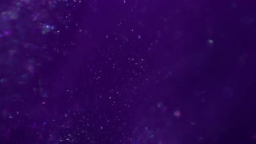 Sparkling glitter floating on a purple background