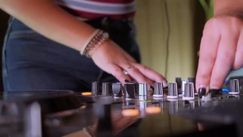 Close-up of a DJ with turning the knobs of the mixer