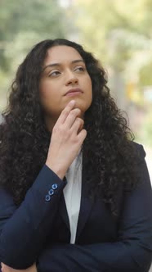 Pensive Young Woman Thinking Outdoors in Business Clothes
