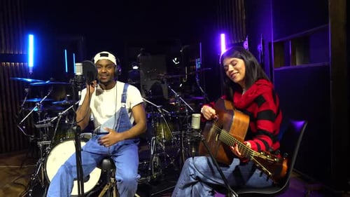 Musicians recording music in studio with acoustic guitar