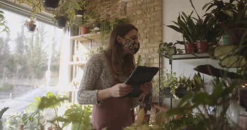 Young adult, female small business owner working on digital tablet in store