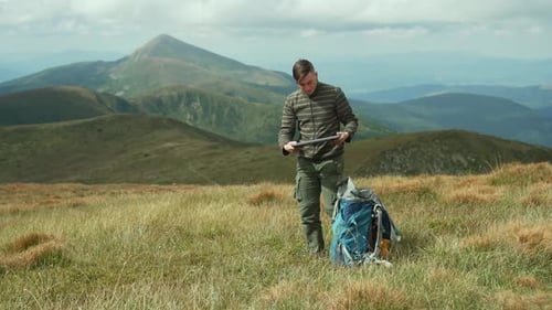 O homem tira o laptop da mochila e se senta para trabalhar ao ar livre