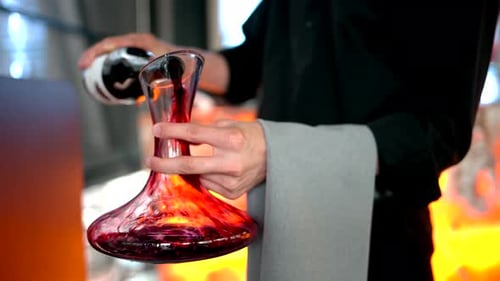 Sommelier et serveur versant du vin rouge dans une carafe en verre, au ralenti