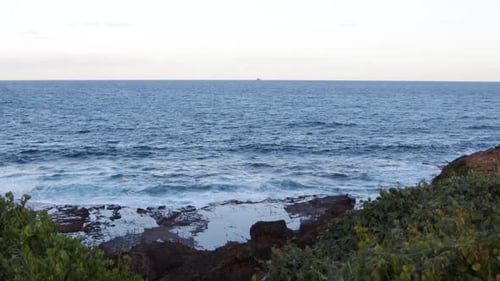 Beautiful vast ocean view with rocky coastline and distant ship