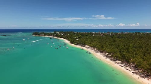 A Speedboat Cruises Across a Beautiful Turquoise Bay Near a White Sand Beach Full of Anchored Yachts