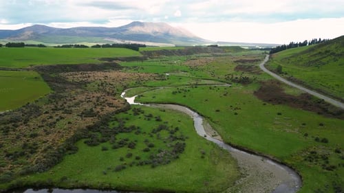 Aerial 4K epic view of a large and idyllic green valley through which a river and a small road pass
