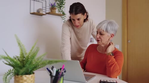 Woman Helping Senior with Computer in Home Setting