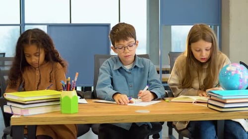 Diverse Group of School Kids with Pens and Notebooks Writing Test in Classroom Education Elementary
