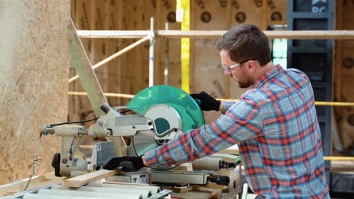Building Contractor Worker Using Hand Held Worm Drive Circular Saw to Cut Boards on a New Home