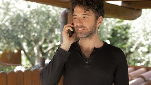 Lächelnder selbstbewusster attraktiver Mann, der im Freien telefoniert. Geräte, Kommunikation