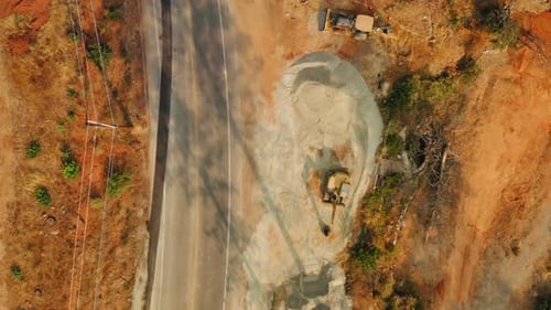 Blick von oben auf eine Baumaschine am Rand einer Autobahnstraße