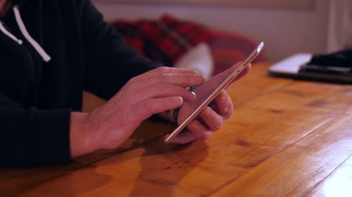 Adult Interacting with Tablet at Wooden Table