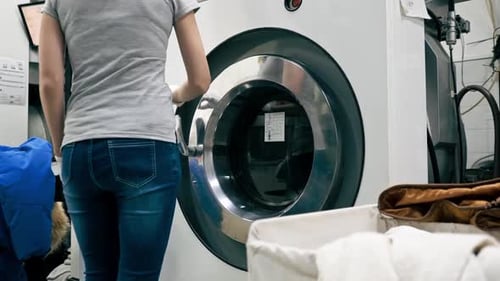 Woman Opening Industrial Washing Machine Door