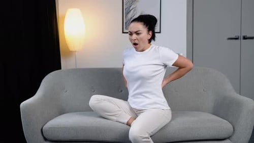 Young Woman Experiencing Back Pain on Couch