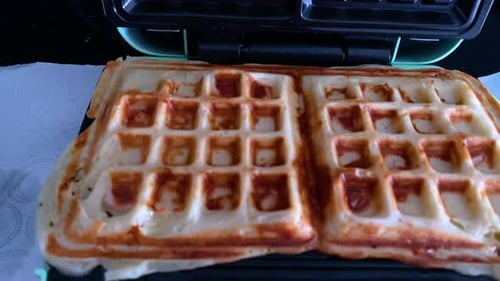 Cooking Waffles In A Waffle Maker,Fresh Dough In A Waffle Maker baked gold.Close up.
