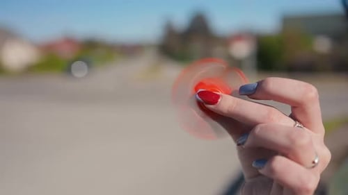 Une image rapprochée montrant une main faisant tourner de manière experte un fidget spinner vibrant et coloré dans une ambiance animée