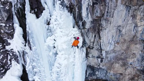 Person Ice Climbing Frozen Waterfall in Winter