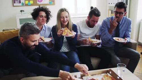 Group Of Young Businesspeople With Pizza Having Lunch In A Modern Office.