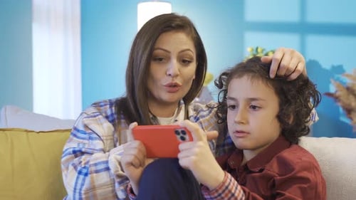 Mother and Son Enjoying Smartphone Together on Couch