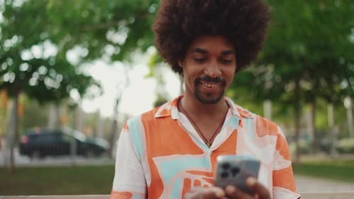 man sitting on park bench using his smartphone