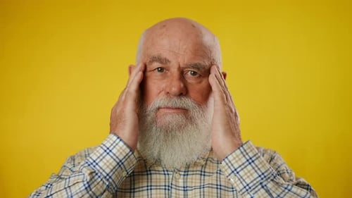 Senior Man with Headache Rubbing Temples on Yellow