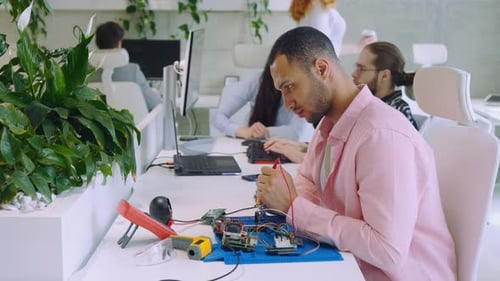 Trabajador masculino serio multiétnico que mide el voltaje con un multímetro