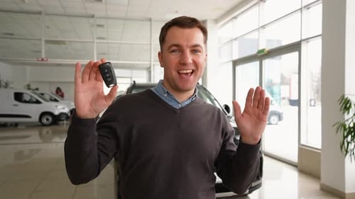 Happy Man Dancing with a New Car Key in Dealership