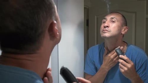 A man shaves his face with a machine.