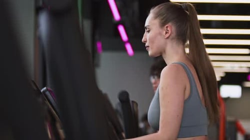 Caucasian Woman Using Elliptical Trainer in Gym