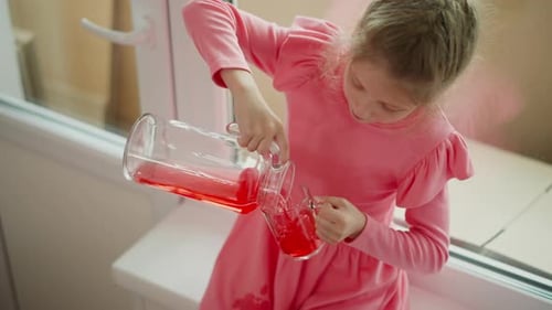 Vue aérienne rapprochée d'un enfant versant du jus rouge à l'intérieur par la fenêtre