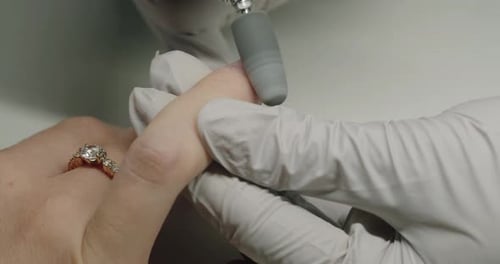 Nahaufnahme eines Maniküristen zur Handentfernung von Gel-Nagellack mit einer Maniküre-Maschine