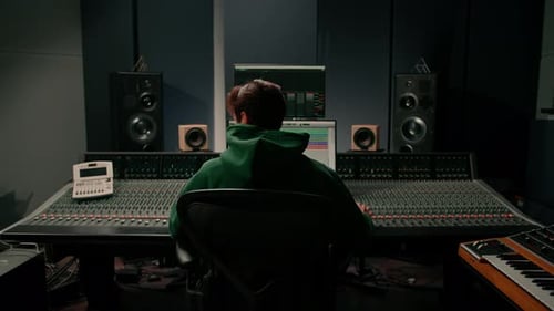 Energetic audio engineer producer working in recording studio mixing tracks on console and hit maker
