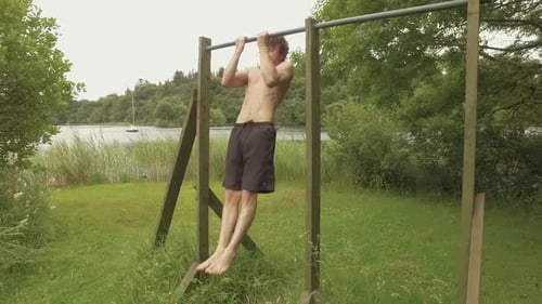 An athletic young man performs close grip chin-ups