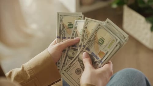 Person Counting Stack of United States Hundred Dollar Bills